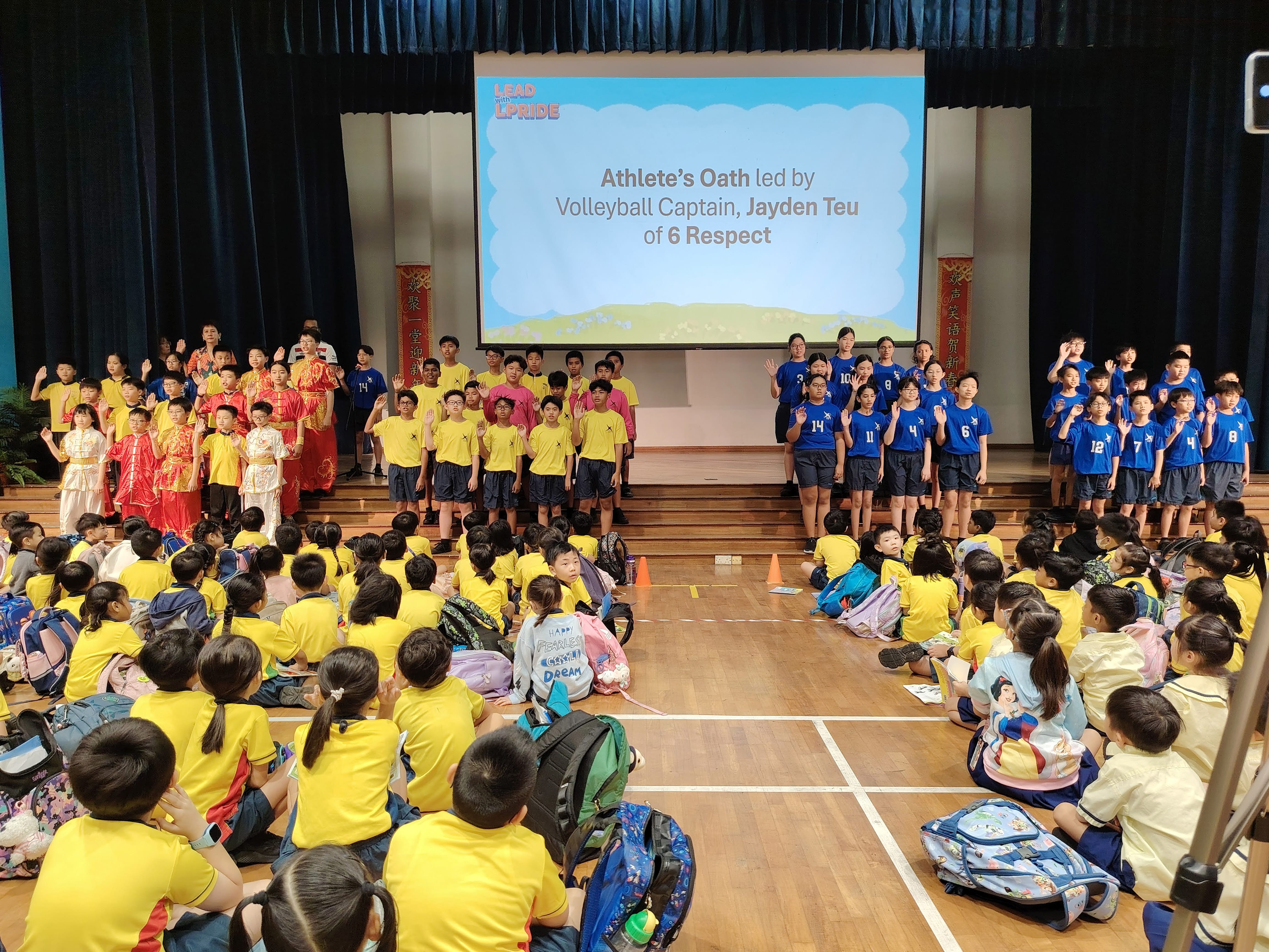 Students stand on a stage taking the Athlete's Oath during a morning assembly